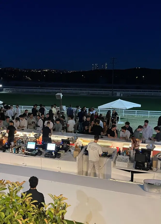 Evento al atardecer en el hipódromo, con la pista llena de invitados